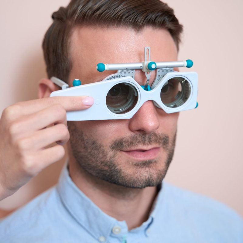 Close up portrait of confident Caucasian man is examining his eyesight in trial frame in the clinic